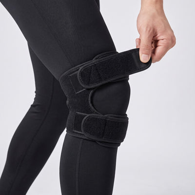 Person adjusting knee strap velcro on black compression tights