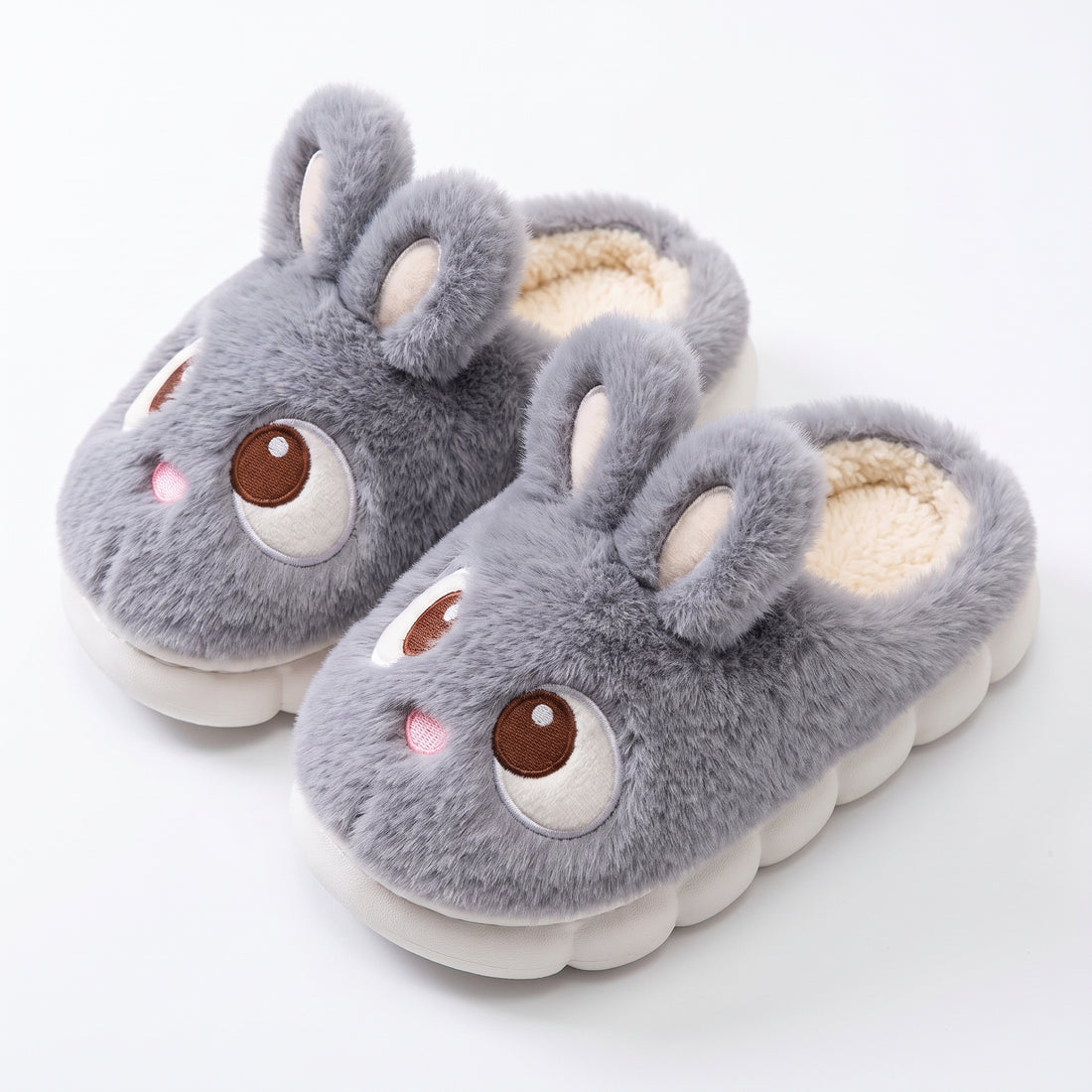 Gray plush bunny slippers with embroidered eyes on white background