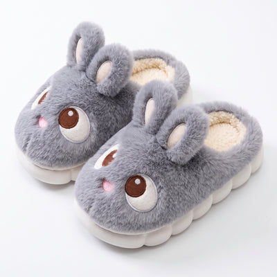 Gray plush bunny slippers with embroidered eyes on white background