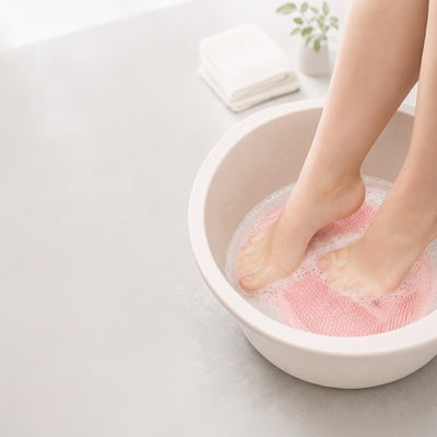 Feet in foot basin with pink silicone scrubber mat
