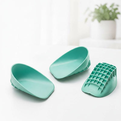 Three green heel cups on white surface with plant