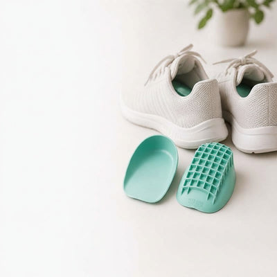 Teal heel cups next to white sneakers on clean surface